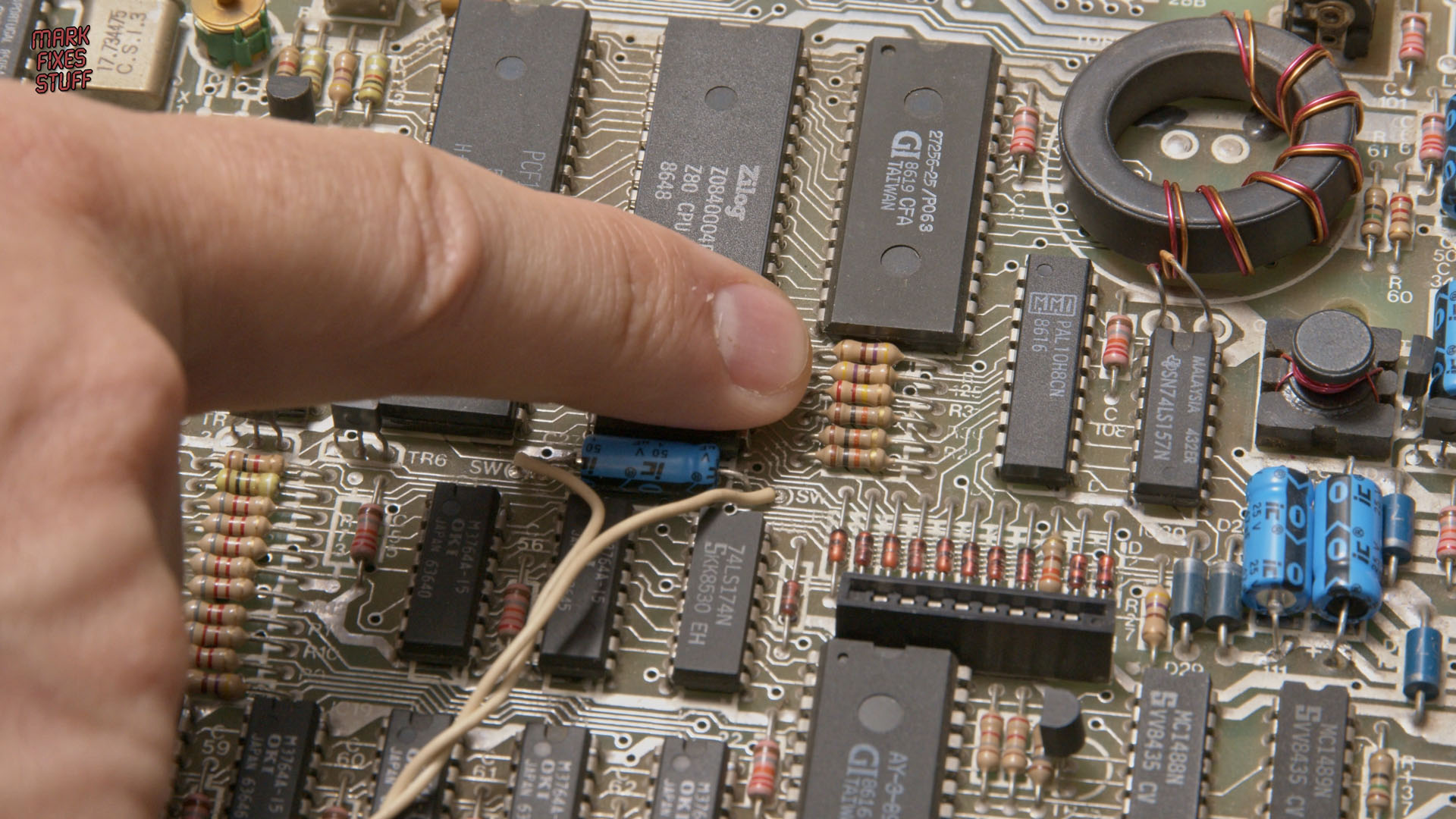 Pointing to an area of concern in a 128k Spectrum during a Mark Fixes Stuff repair video