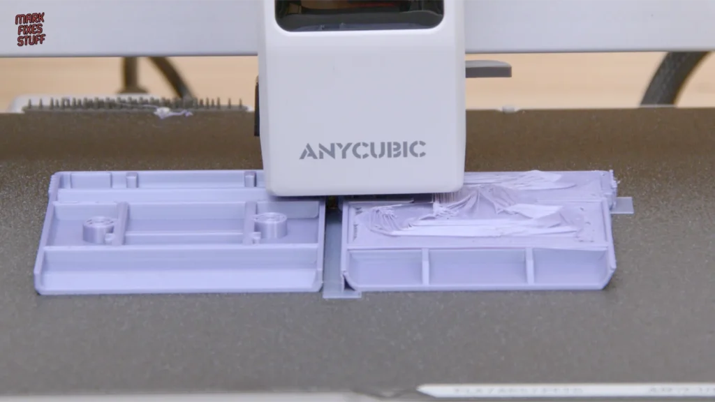 A failed spaghetti 3D print beside a successfully printed purple cartridge shell half
