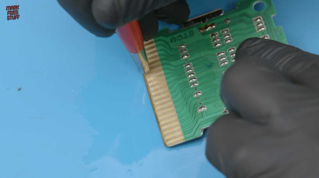 Cleaning the gold card edge contacts of an Intellivision cartridge PCB with a fibreglass pencil