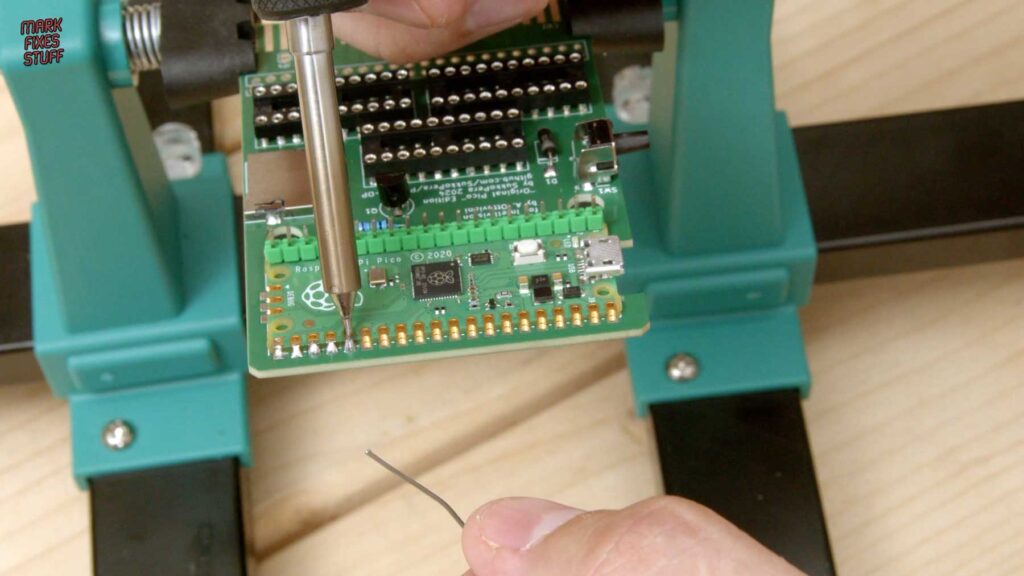 Soldering a Raspberry Pi Pico to the castellated pads of an Intellivision multi-cart PCB held in a board holder