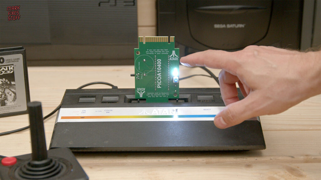 Pico A10400 circuit board fitted in an Atari 2600 Junior, with Mark pointing to its illuminated LED